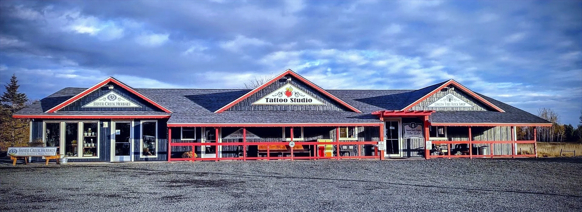 The Crimson Heart Designs building on Highway 8: a grey building with red trim and a Tattoo Studio sign over the porch